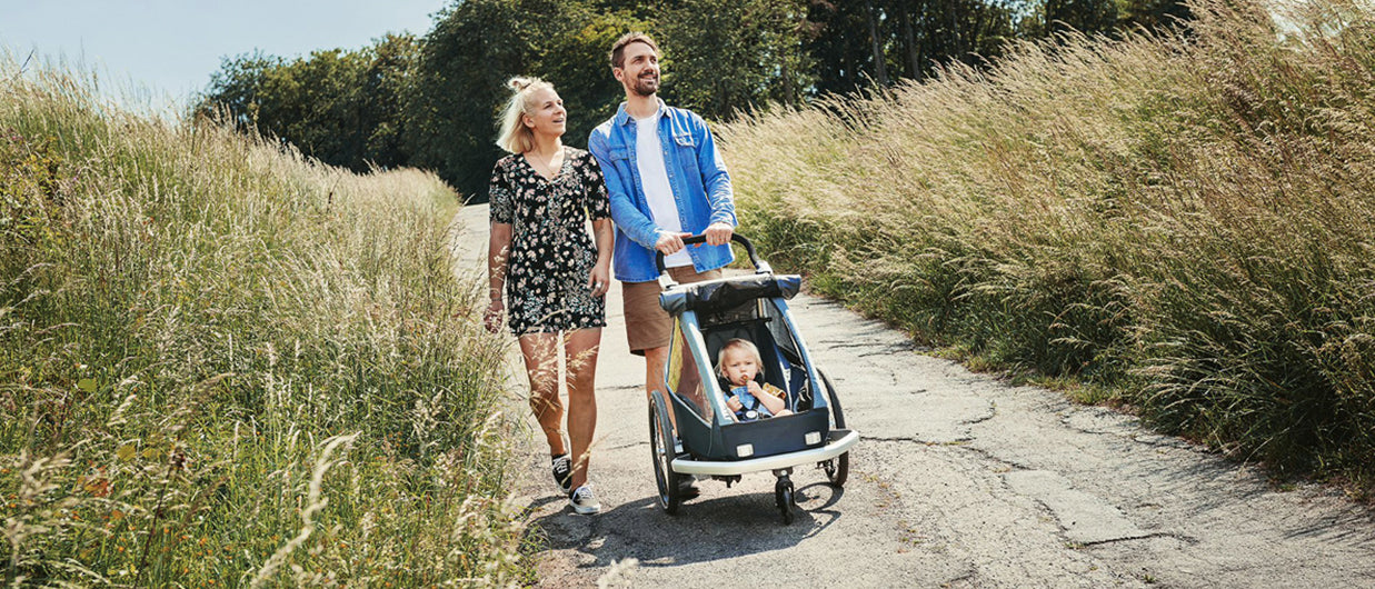 Happy family enjoying nature with child in Croozer Kid trailer functioning as a buggy